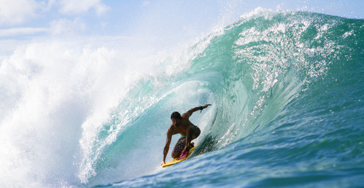 A bodyboarder rides in the drop knee riding style in a barrel wave