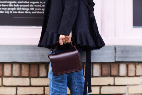 Woman wearing blak suit holding her purse on street