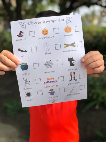 boy holding up Halloween Scavenger Hunt printable