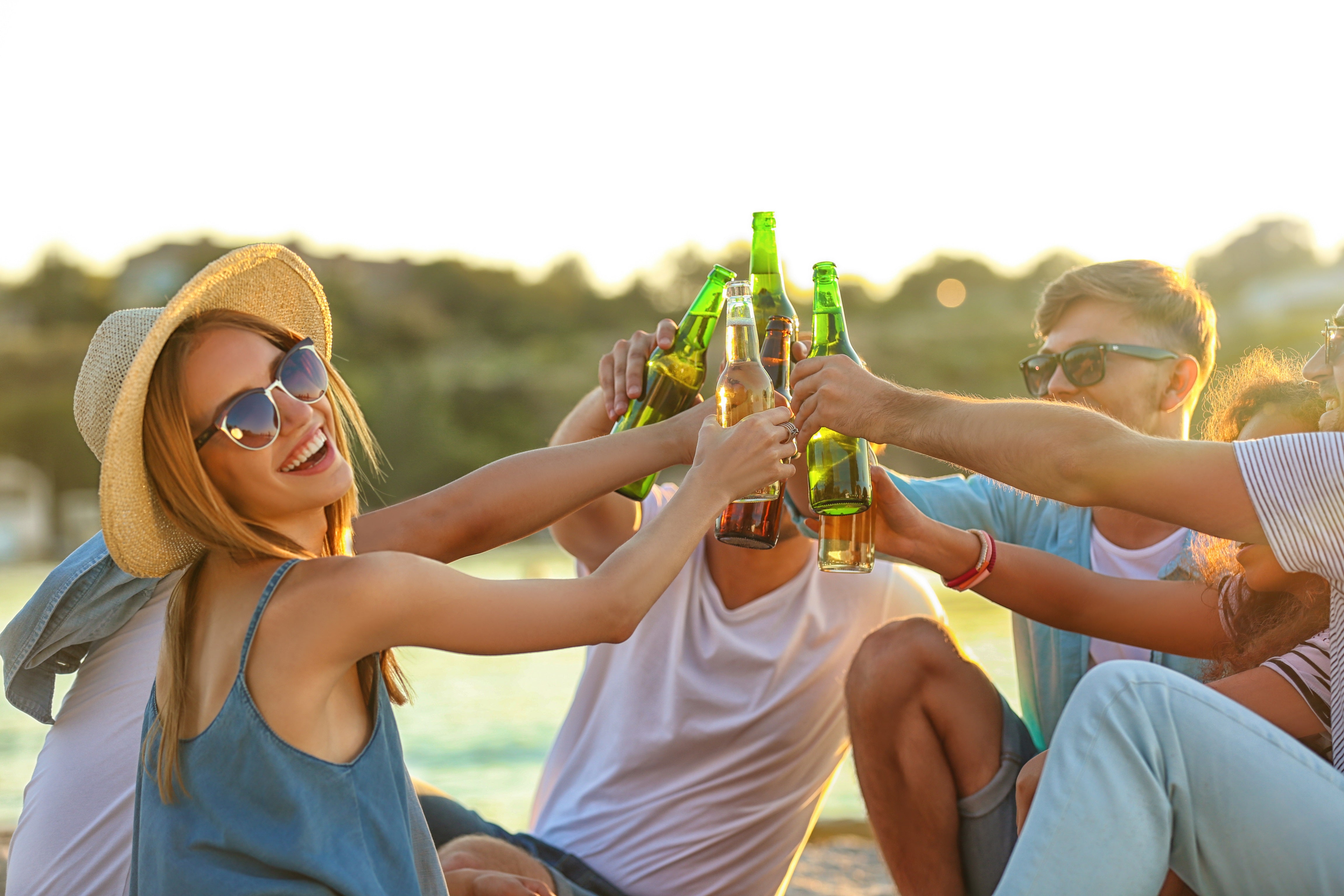 група приятели празнуват на плажа с бири