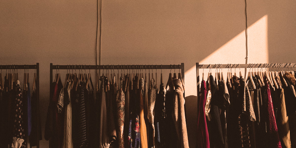 Clothing rack with diverse garment sizes and styles, unsegregated by gender, photographed in a studio.
