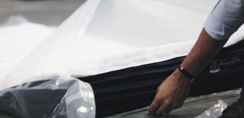 Hand unwrapping mattress to let air in