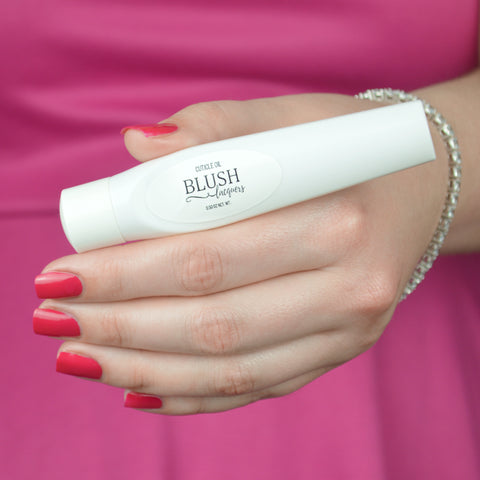 BLUSH Lacquers Bubblegum Cuticle Oil being held by a woman in a hot pink dress.