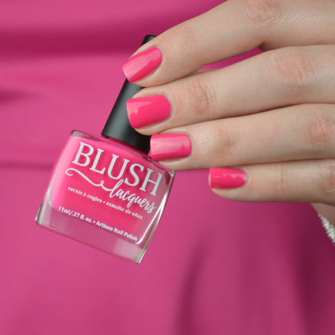 BLUSH Lacquers Dream House light magenta pink nail polish bottle being held by a woman in a hot pink dress.