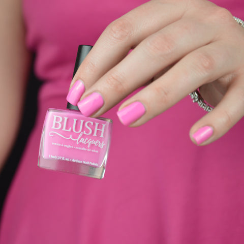 BLUSH Lacquers Little Pink Corvette Bubblegum pink nail polish bottle being held by a woman in a hot pink dress.