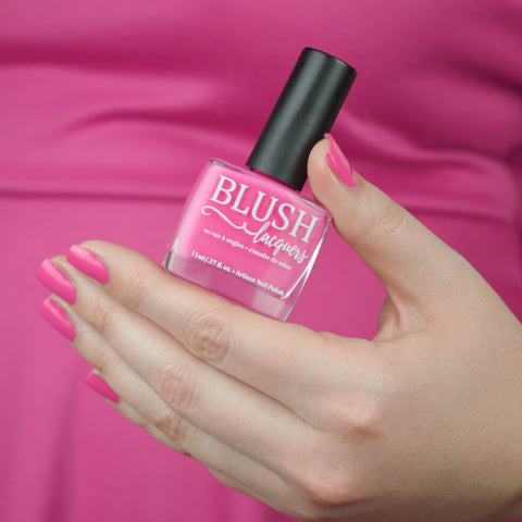 BLUSH Lacquers Shopping Spree hot pink nail polish being held by a woman in a hot pink dress.