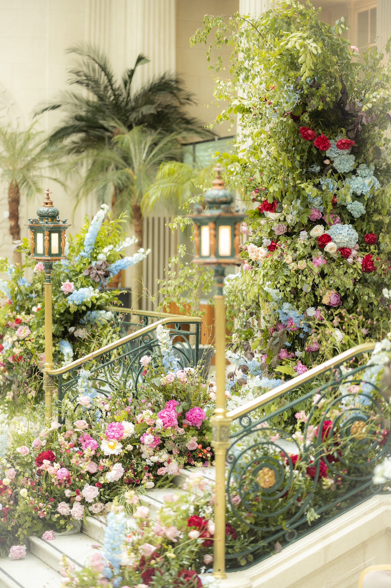 Detail of The Waldorf Hilton's Palm Court stairs finely decorated with lush botanicals and vibrant blooms designed, created and installed by Event Florist Amaranté London - Bespoke floral arrangements providing a sophisticated and inspiring atmosphere for grand weddings.