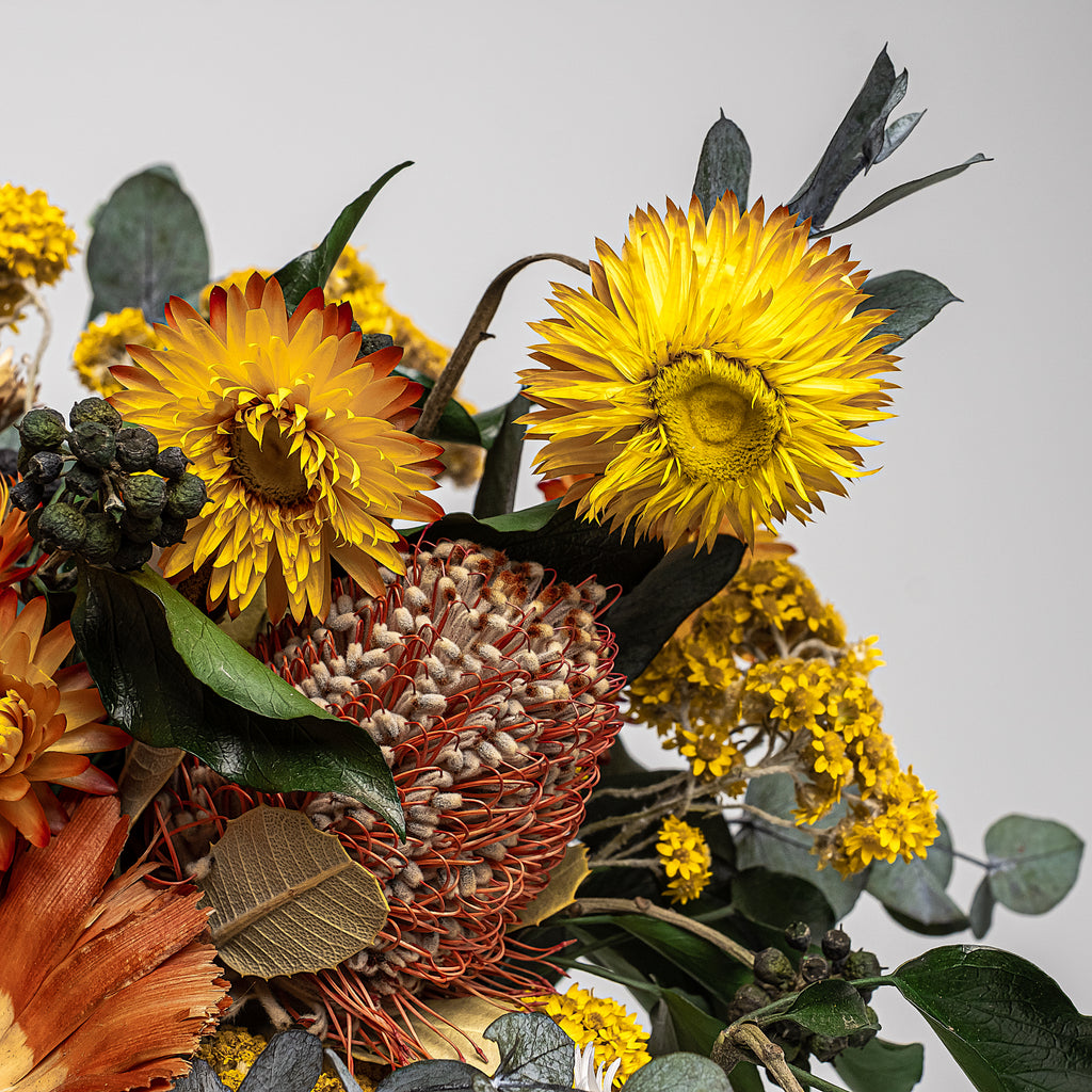 The Dried Flower Bouquet that will warm up your wedding reception with its delicate Achillea. This bouquet features comforting autumn colours that complement each other for a comforting warm autumn feeling everyone will enjoy at the wedding reception.