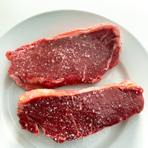 Raw salted and oiled steak on a plate 