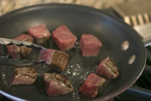 Cut PRE Filet Mignon into 9 squares. Preheat a skillet to medium-high heat on the stove and heat olive oil. Once hot, place all the squares in the pan and sear on each side for 30 seconds. Remove from pan and set aside. 
