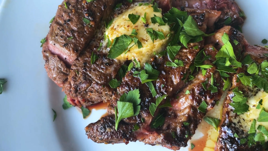 A melted pad of butter with herbs on top of a sliced steak