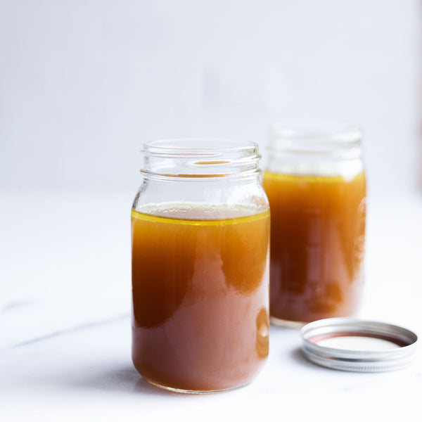 Jars of Bone Broth next to each other with a cap on the counter