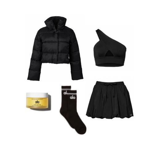 An image of product flatlays including Magic Multi-Balm, a black bubble skirt, a black one-shouldered bra top with front cutout, black and white crew socks with an Alo logo, and a black puffer jacket. 