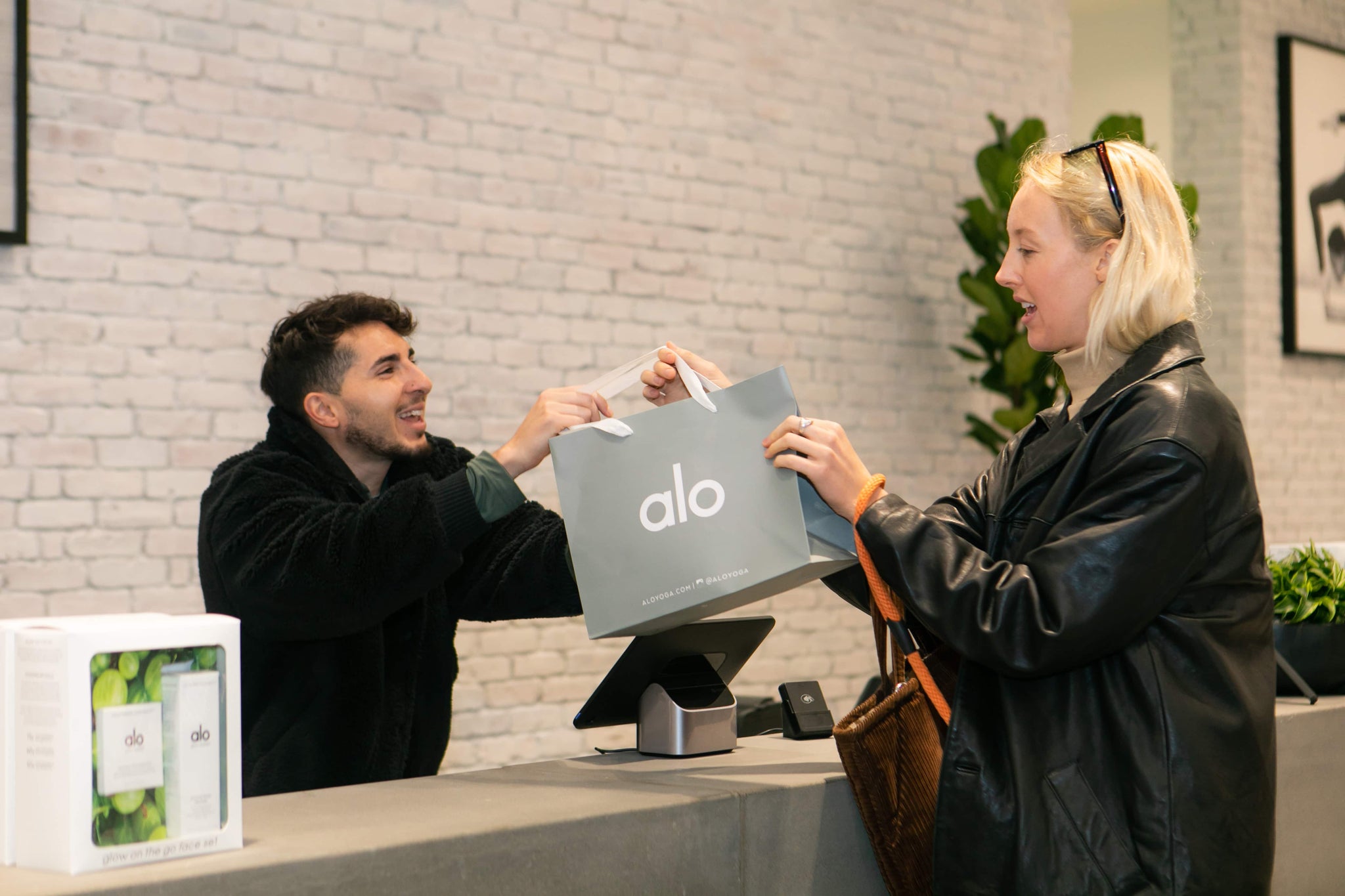 A woman being handed an Alo Yoga bag while purchasing clothing at the Fashion Island Alo Yoga store in Newport Beach, California. 