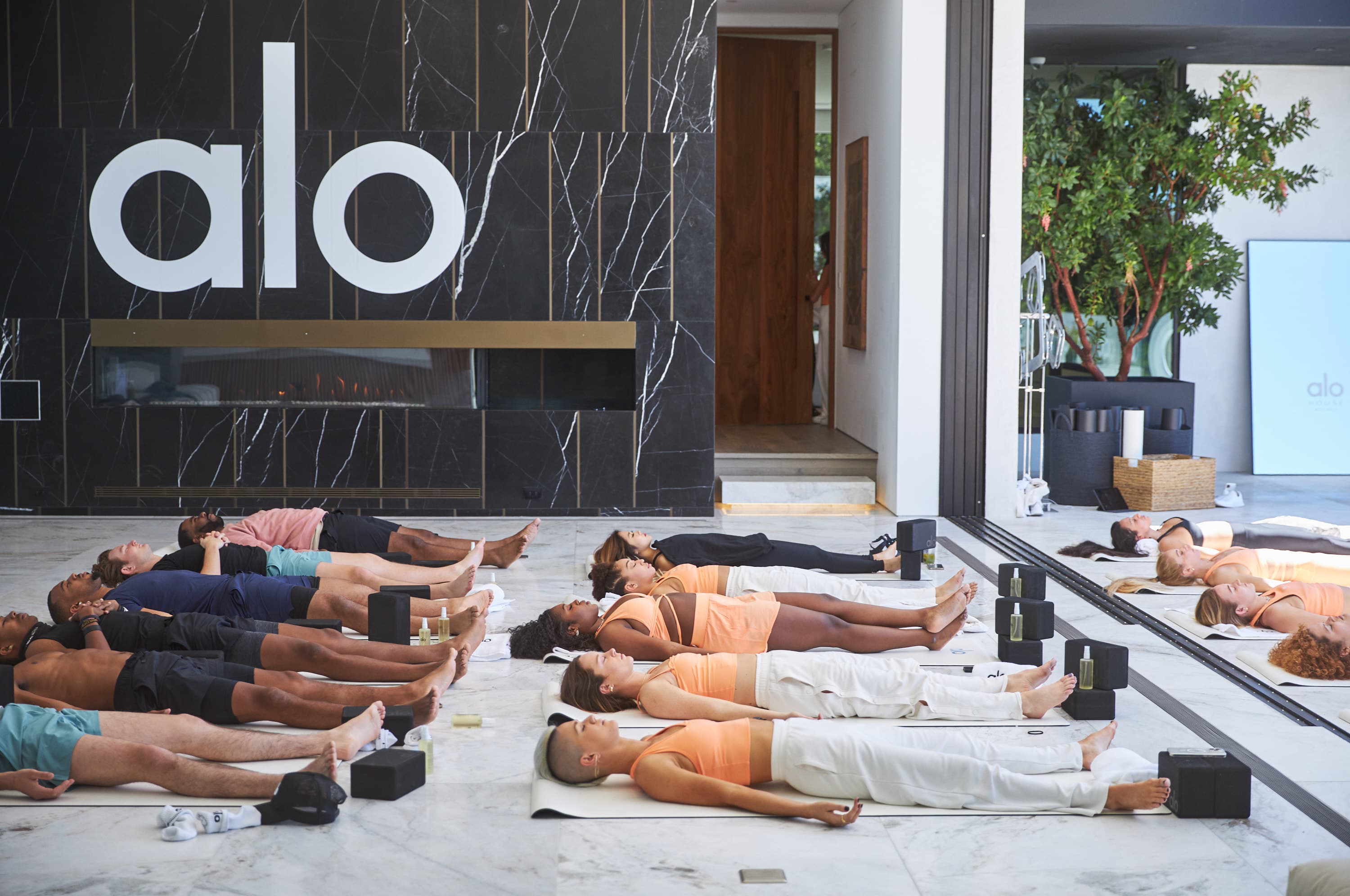 A group of people in Savasana after a yoga meditation at the end of Alo Wellness House. 