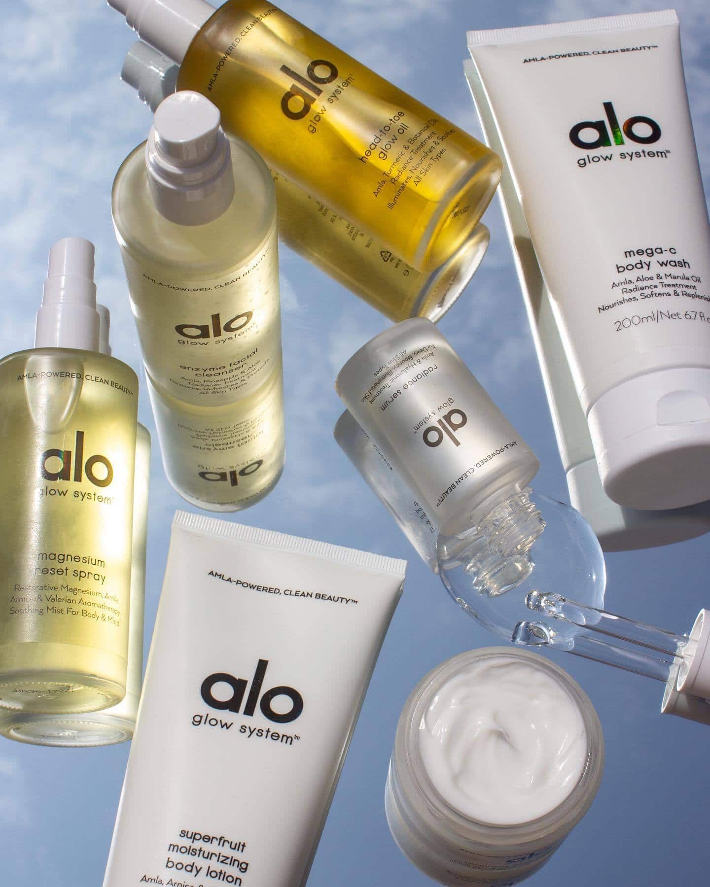 Flat mirror lay of Alo Glow System products, cream opened, and bottles tipped over. 
