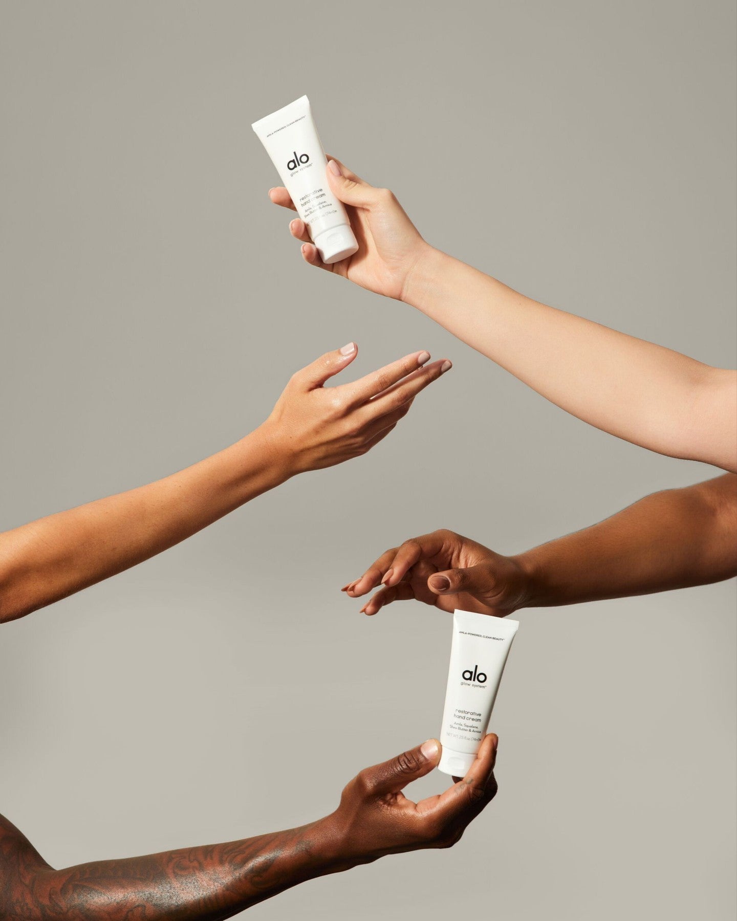 Hands and arms of different colors and genders holding Restorative Hand Cream 