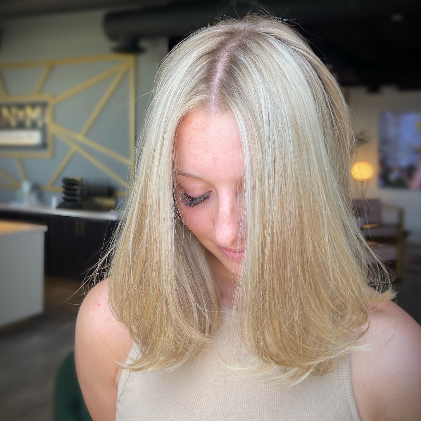Downward shot of blonde woman’s part showing shiny, healthy hair and scalp.