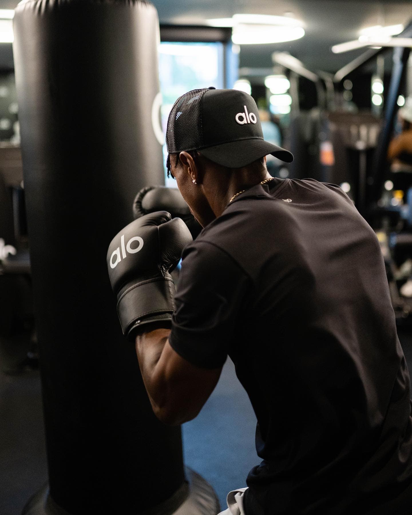 @x.flowers4 wearing a black Alo trucker hat while boxing in the Alo HQ gym.  