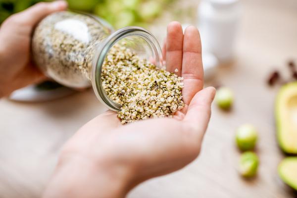 Hemp seeds in a glass jar being poured into a hand