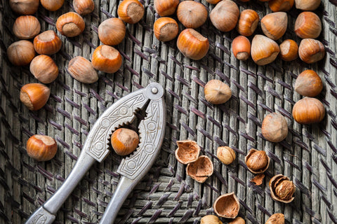 A group of hazelnuts and a nut cracker.