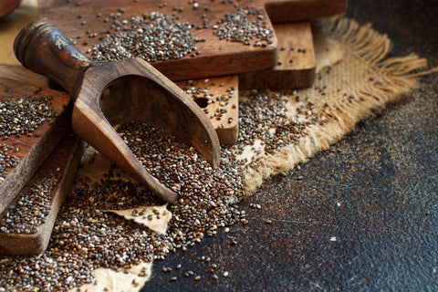 Chia seeds spilt across wooden chopping boards and a matt