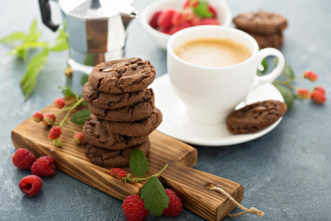 A stack of Chocolate cookies with a cup of coffee next to it.