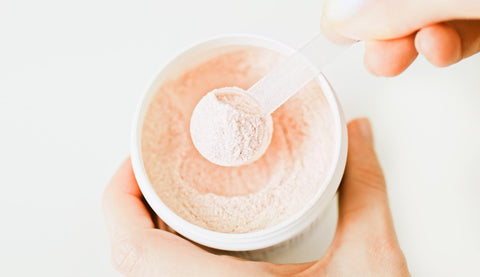 A person scooping protein powder out of a container.
