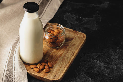 Almond milk in a jar next to a bowl of almonds.
