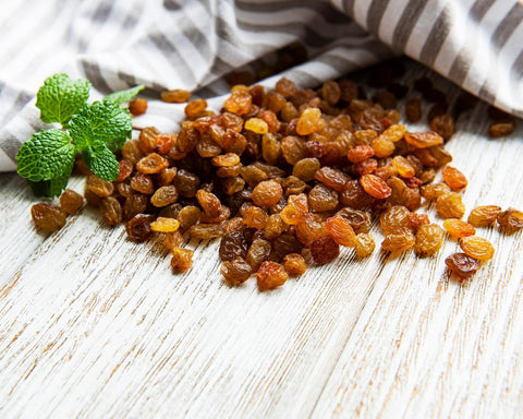 Golden yellow sultanas spread out across a wooden chopping board