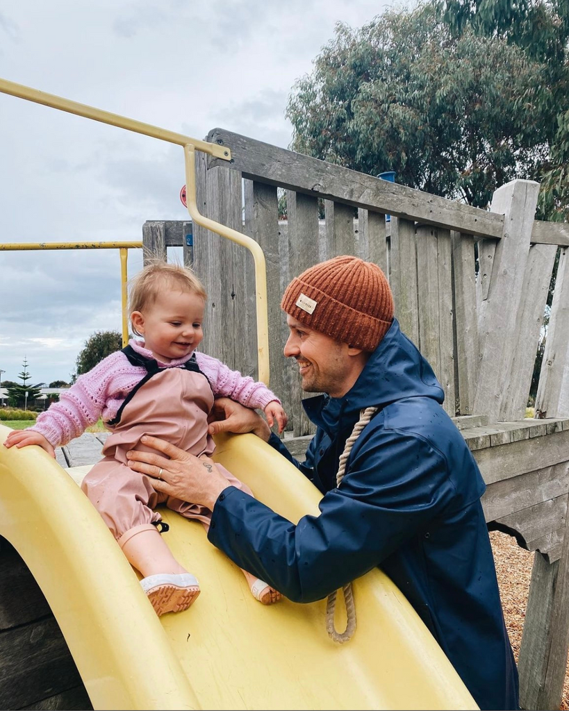 A dad plays with his child while wearing a navy unisize raincoat