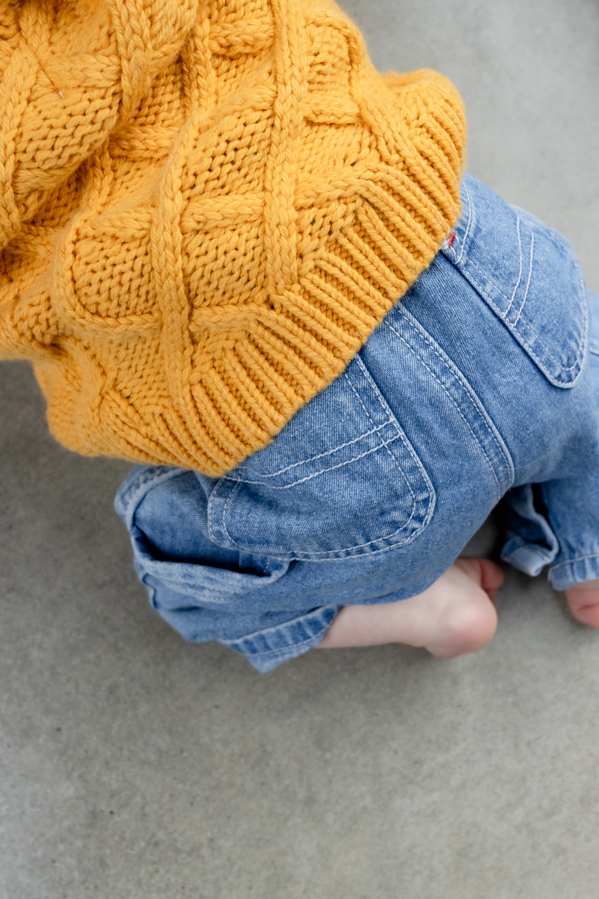 A baby wearing a mustard knit