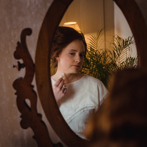 Victorian woman in mirror applying perfume by Willow & Birch Apothecary