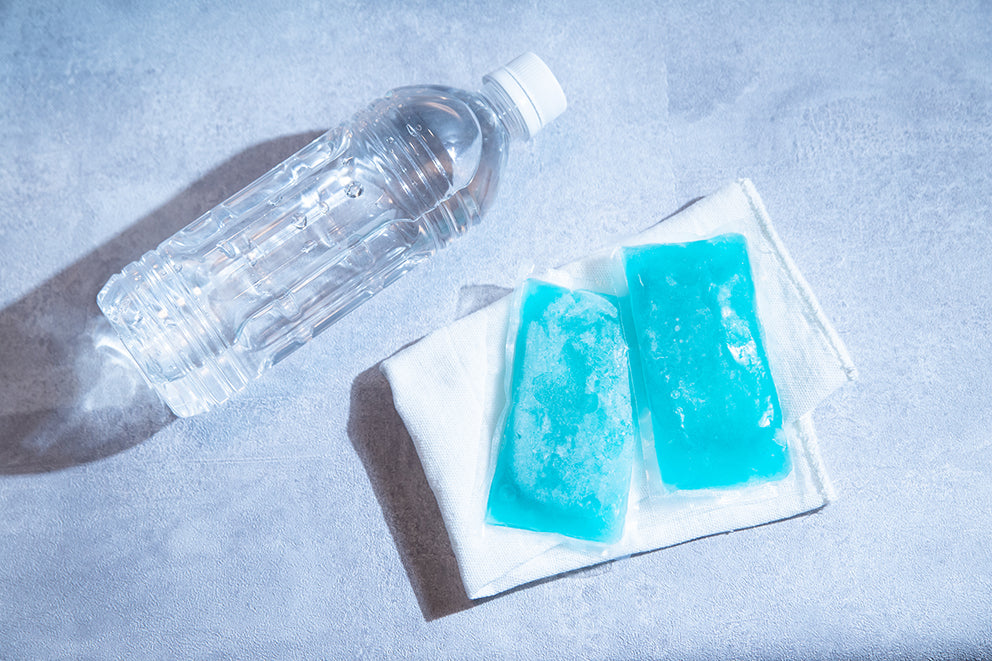 a bottle of water next to a pair of ice packs and a towel