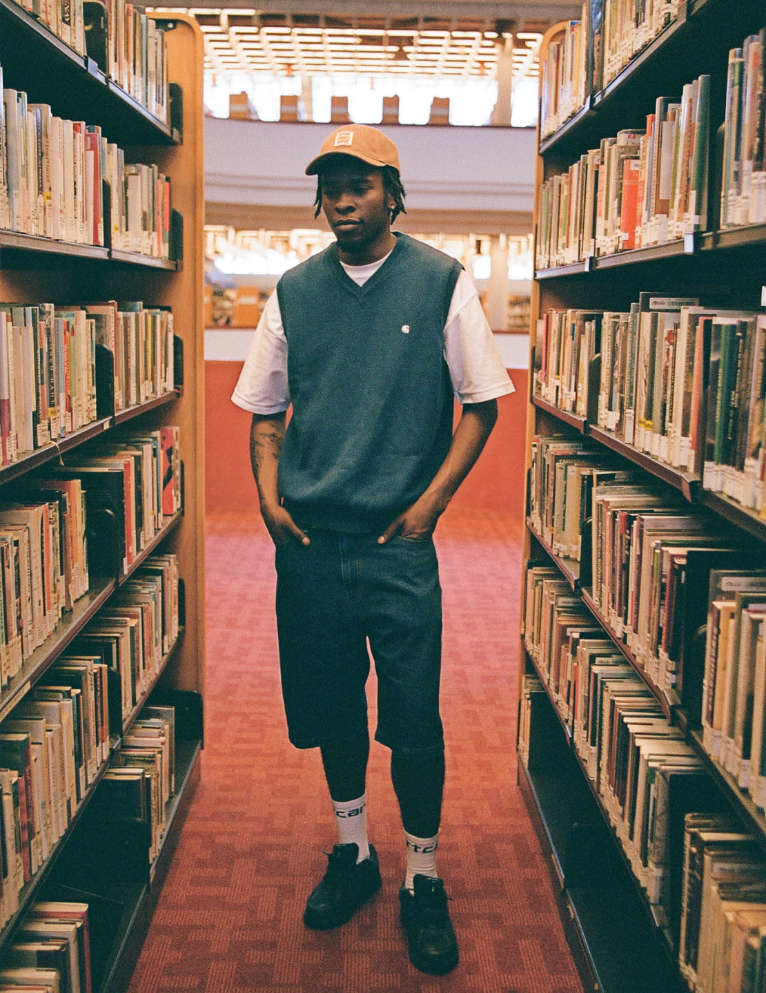 Model in Library wearing Carhartt WIP Madison Vest Sweater in Elder