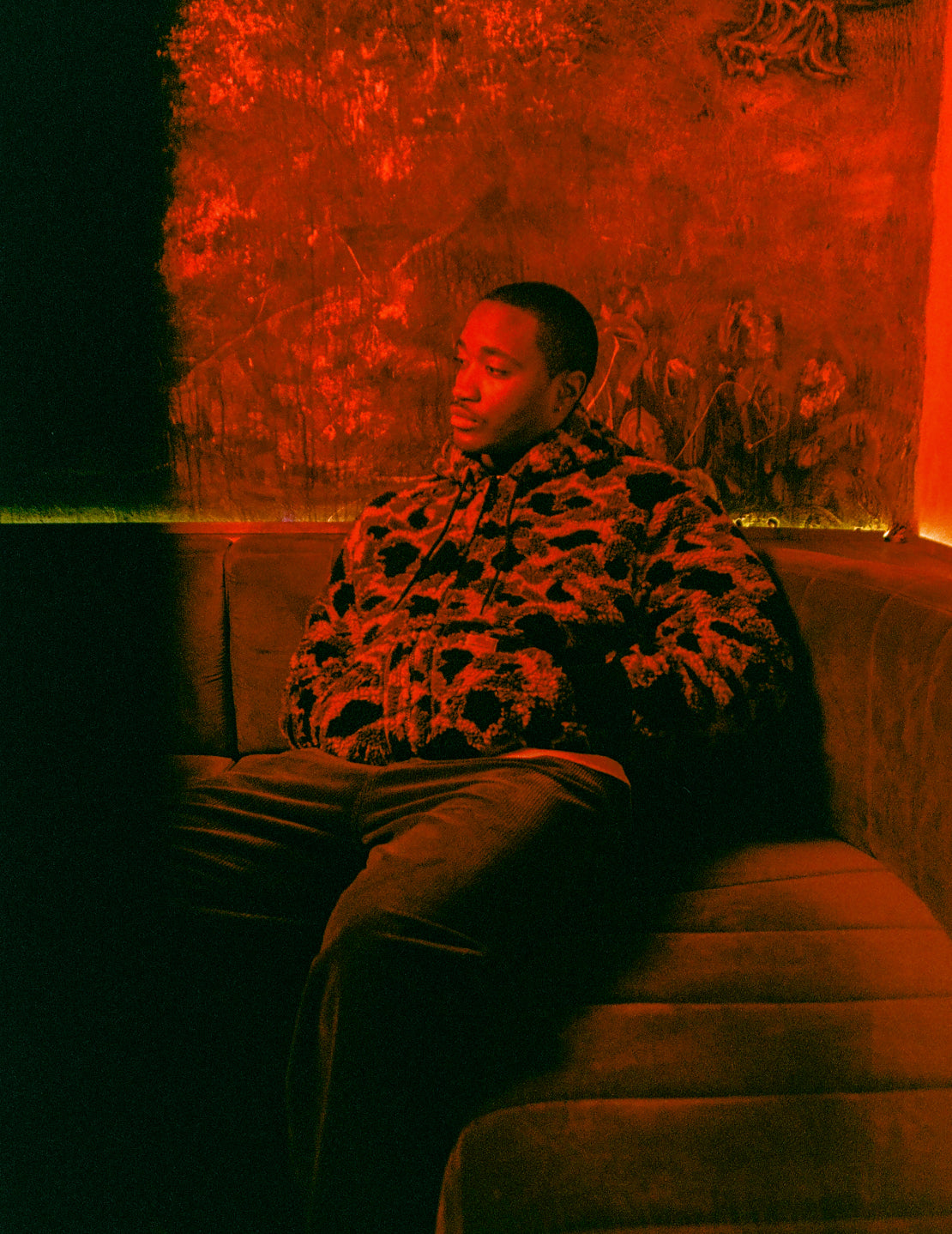 Model sitting in a red room wearing an OG Active Liner in Green Camo Duck