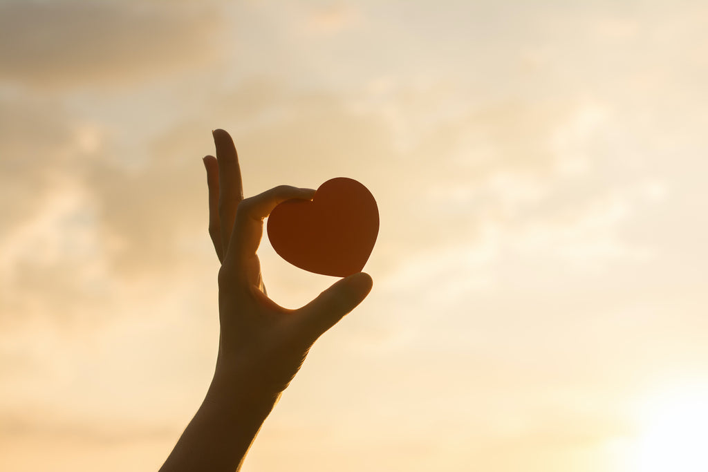 A hand holds up a heart-shaped cutout 