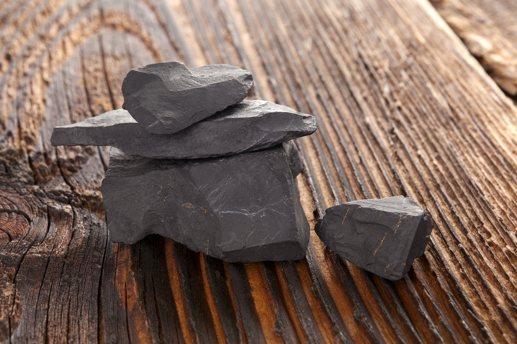 A stack of raw shungite stones on a wood surface