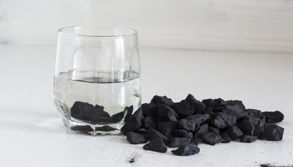 Piedras de Shungit utilizadas para purificar un vaso de agua