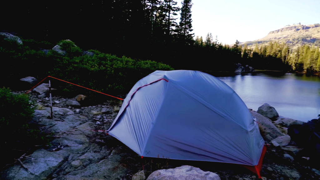 A camping tent set in front of a river.