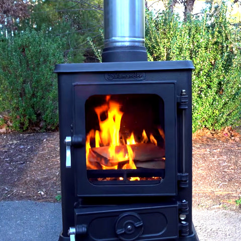 A burning wood stove located in the outdoors.