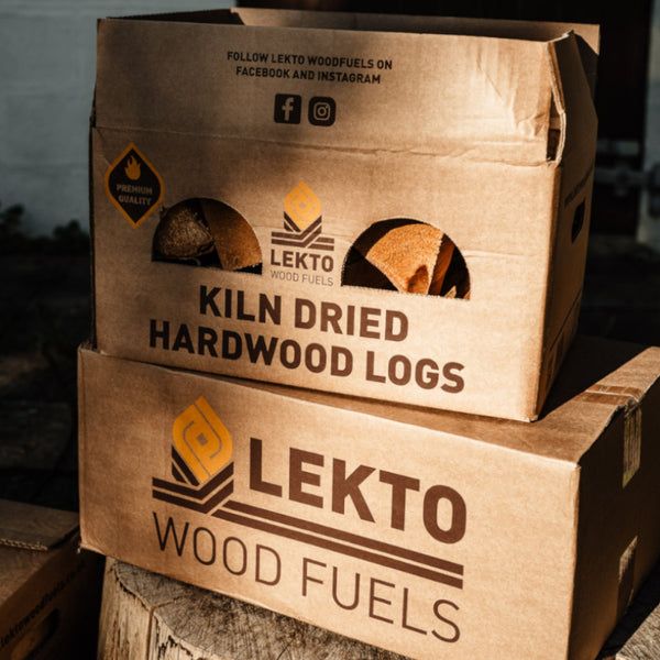 2 Boxes of Lekto Wood Fuels Hardwood Heat Logs piled on a tree stump