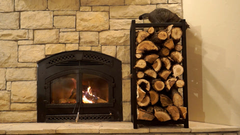 A free standing log holder next to a burning log burner.