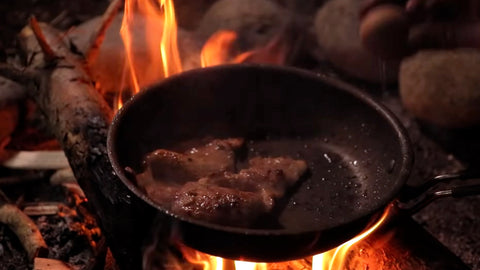 Meat cooked in a skillet on an open fire.