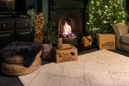 glowing fireplace next to Christmas tree with Lekto wood fuels boxes in front