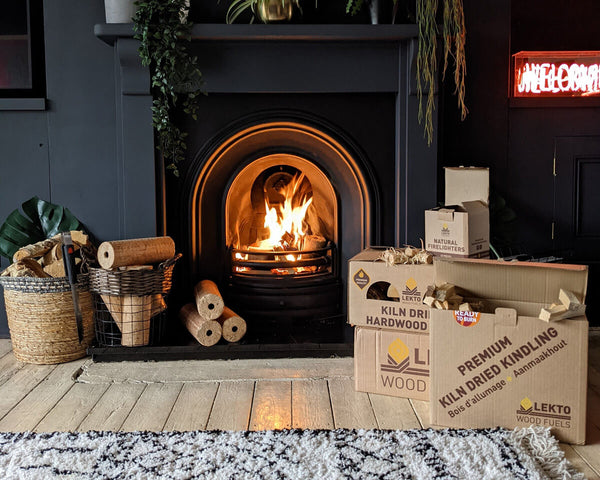 Kiln Dried Kindling and birch logs in a lounge next to a lit fire place  