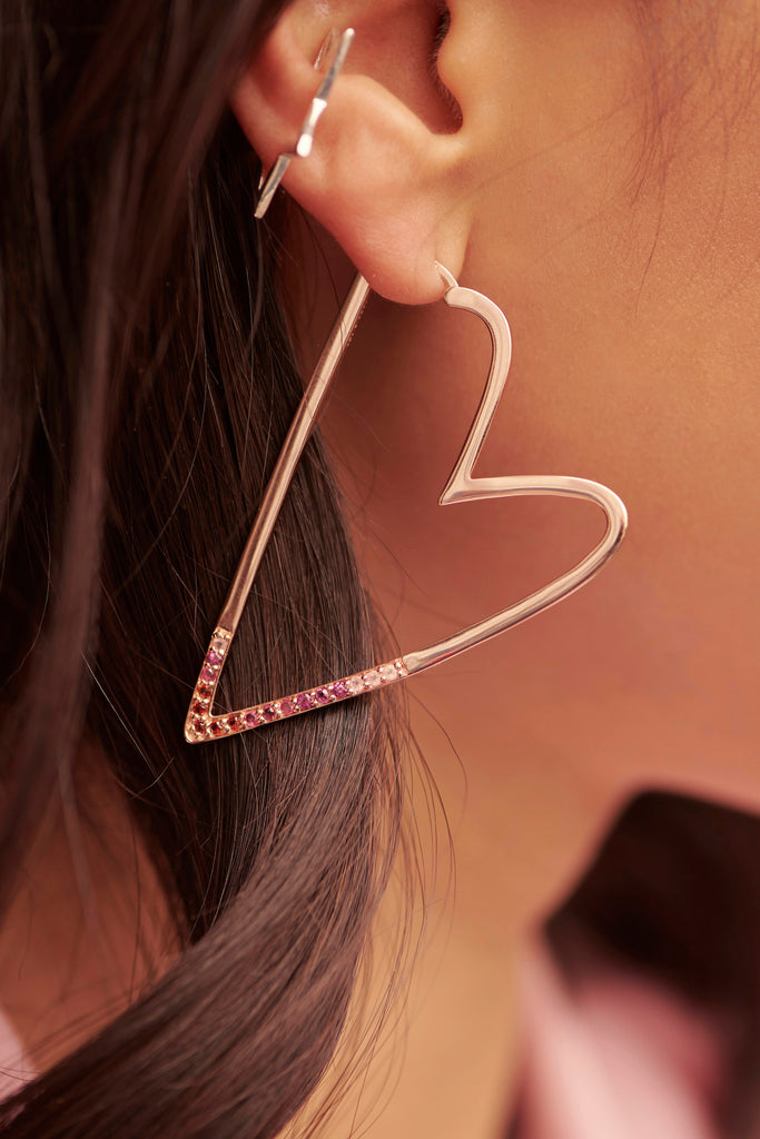 Close up photo of woman's ear wearing a large heart earring and star earring