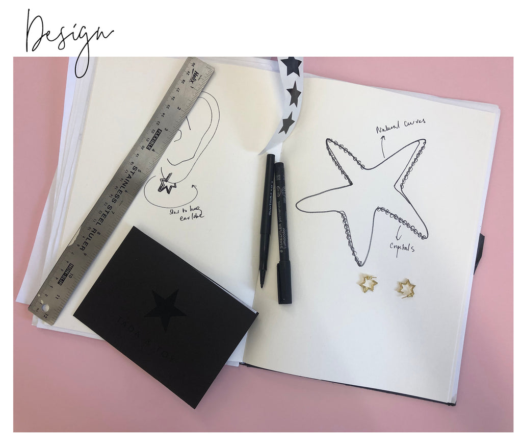 Design sketchbook, with sketches highlighting the natural curves of a star and what it would look like on a person's ear. Two golden samples sit on the sketchbook.