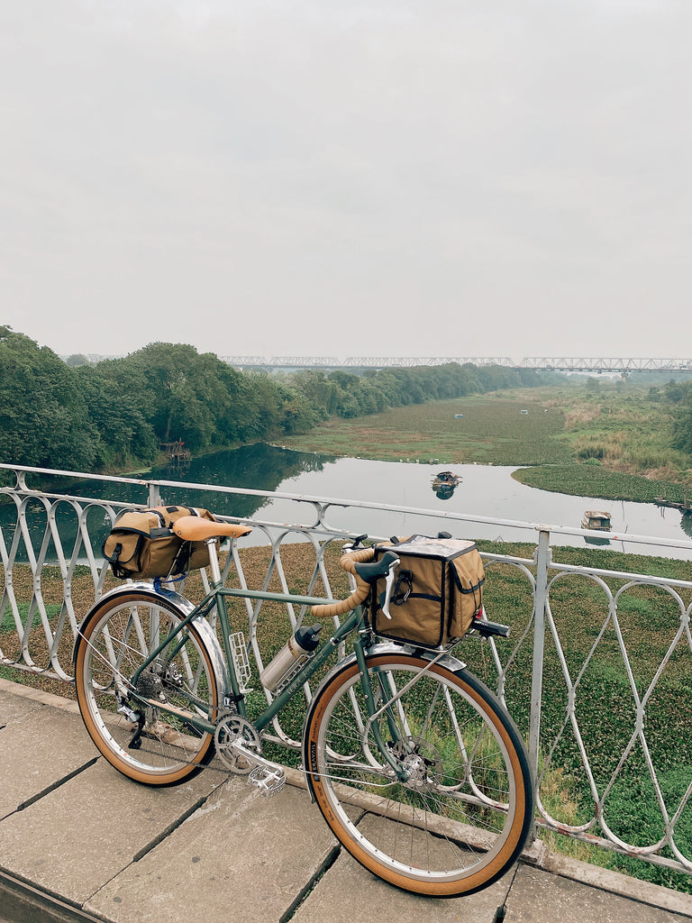 velo orange polyvalent with tan tires and tan bags on a bridge