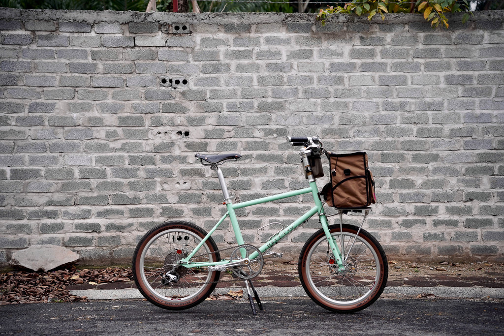 velo orange neutrino mini velo with swift industries bag against a stone wall